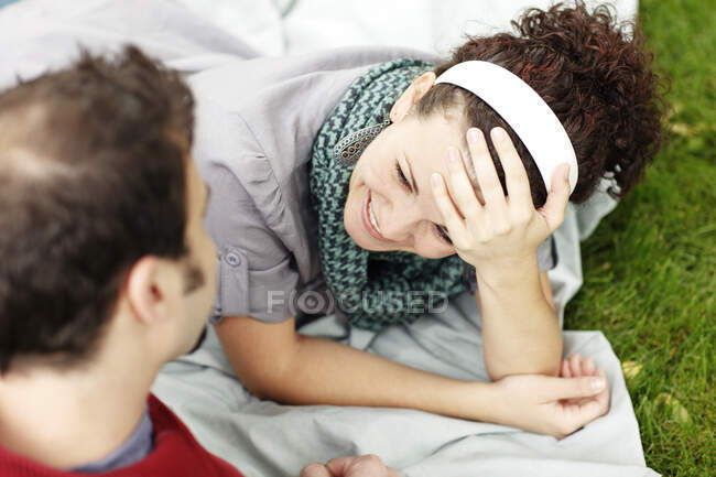 Woman smiling at her partner while laying on blanket in the gras — Stock Photo