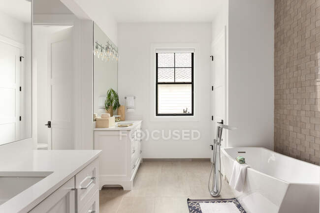 Интерьер современной ванной комнаты с белыми стенами и большим окном — стоковое фото