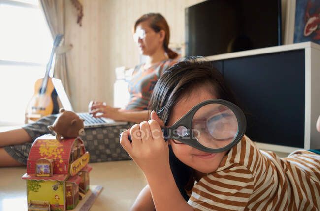A girl is playing nearby a mother who is working with a laptop — Stock Photo