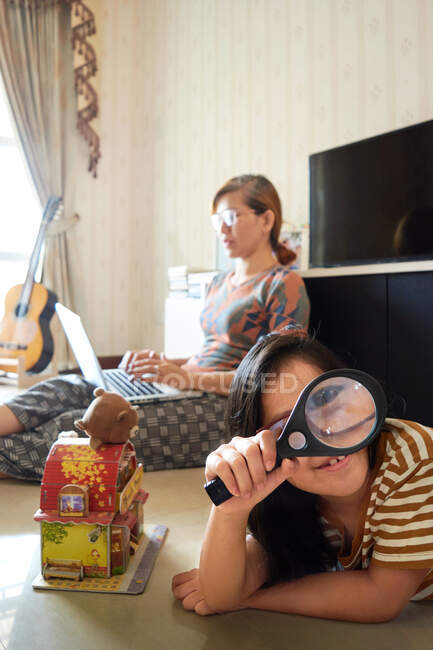 Uma menina está brincando nas proximidades de uma mãe que está trabalhando com um laptop — Fotografia de Stock