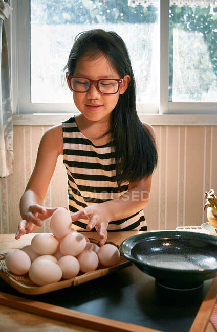 Uma menina organiza os ovos em uma bandeja de bambu — Fotografia de Stock