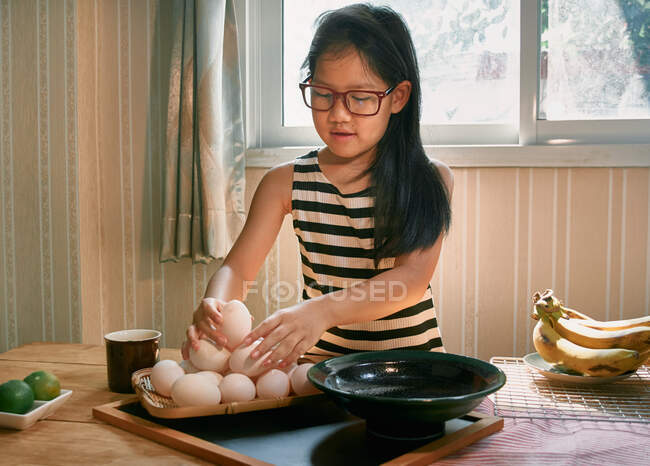 Une fille arrange les œufs sur un plateau en bambou — Photo de stock