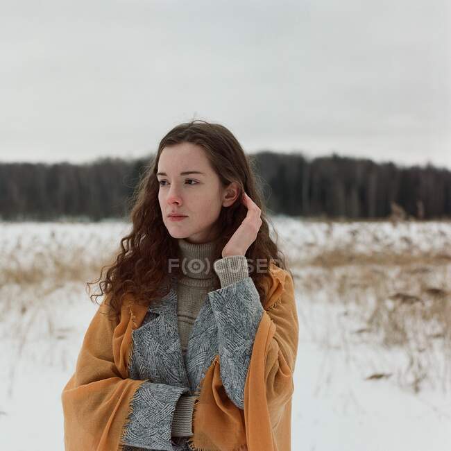 Жінка стоїть на березі замерзлого озера в жовтому шарфі — стокове фото