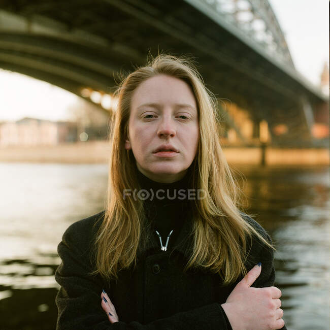 Una donna si trova al tramonto vicino al ponte — Foto stock