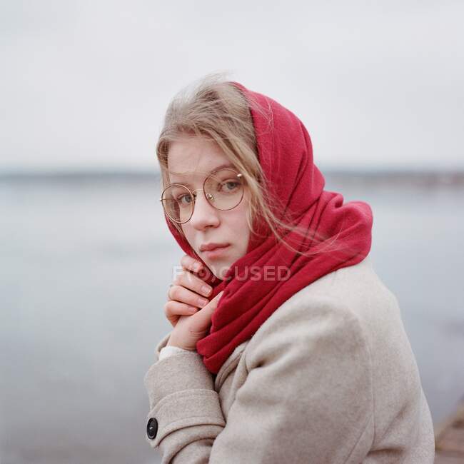 Жінка стоїть на березі річки в червоному шарфі. — стокове фото
