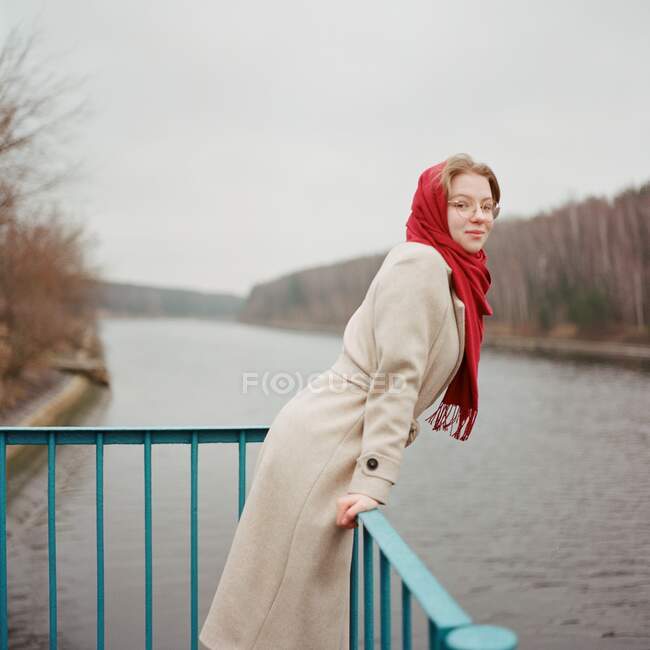 Una donna sta sulla riva del fiume con una sciarpa rossa — Foto stock