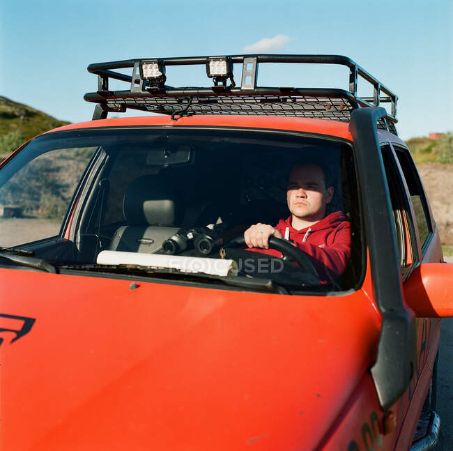 Um homem senta-se ao volante de um carro com um mapa e binóculos — Fotografia de Stock