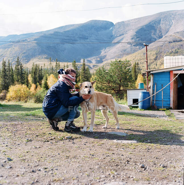 Mulher sentada ao pé da montanha com um cão — Fotografia de Stock