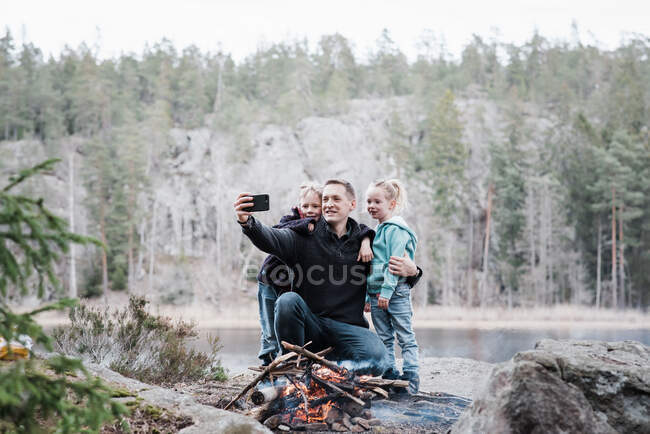 Father taking pictures with his kids whilst enjoying a campfire — Stock Photo
