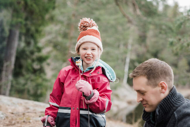 Young girl smiling whist eating a marshmallow whilst camping in Sweden — Stock Photo