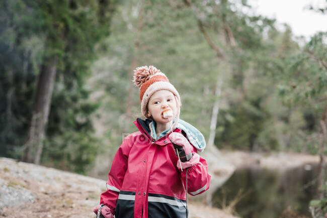 Menina comendo marshmallows enquanto acampando em uma floresta na Suécia — Fotografia de Stock
