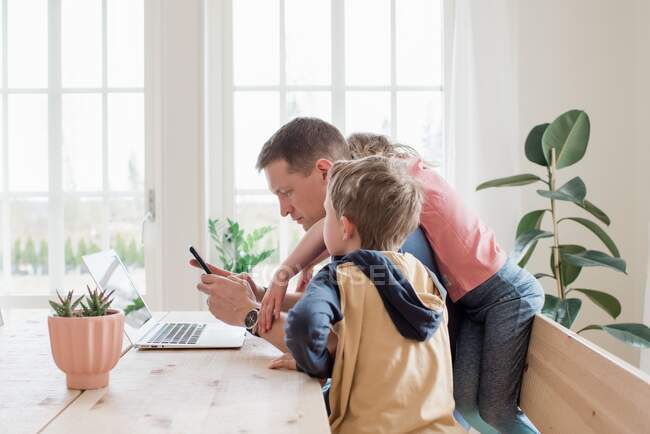 Father working from home with his kids climbing over him — Stock Photo