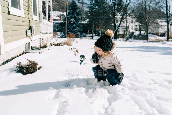 Маленька дитина їсть сніг у саду . — стокове фото