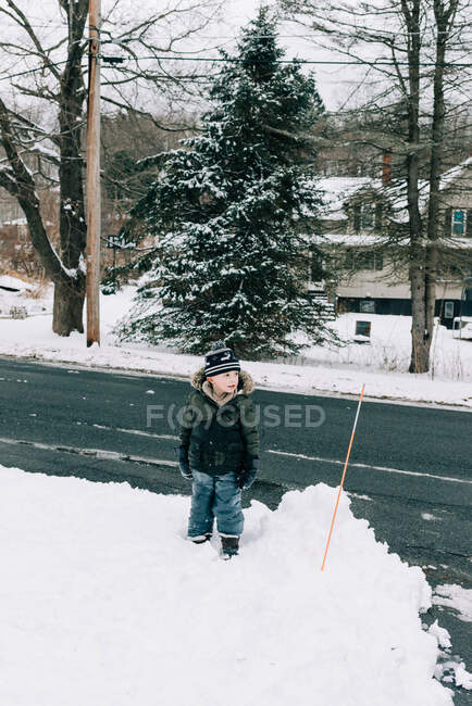Niño parado en la nieve con su sombrero torcido. - foto de stock