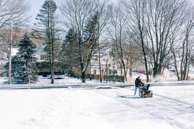 Jeune homme labourant son allée après une tempête hivernale. — Photo de stock