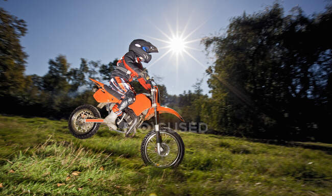 12 ans garçon sautant avec sa moto hors route — Photo de stock