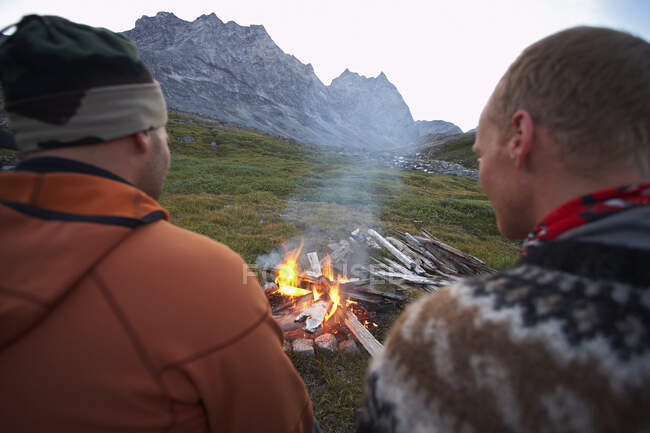 2 amigos do sexo masculino sentados em um incêndio no acampamento na Groenlândia — Fotografia de Stock