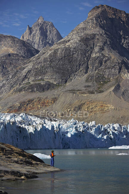 Uomo in piedi sul bordo dell'acqua di un fiordo in Groenlandia — Foto stock