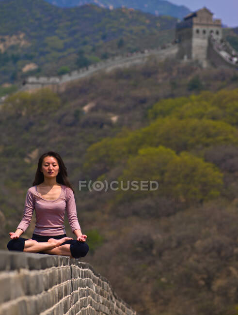 Chinese woman meditating on the Great Chinese Wall — Stock Photo