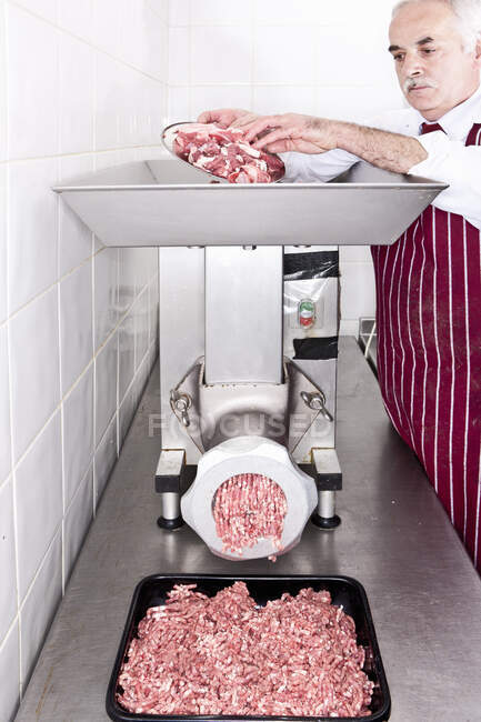Butcher grinding meat in shop — Stock Photo