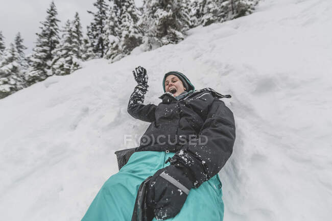 Giovane donna con cappello scorrevole veloce nella neve discesa faccia divertente — Foto stock