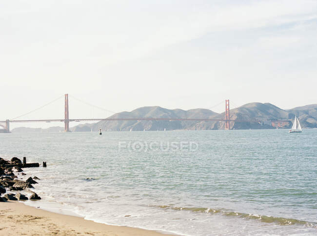 Golden Gate bridge from the shore of San Francisco with Sailboat — стокове фото