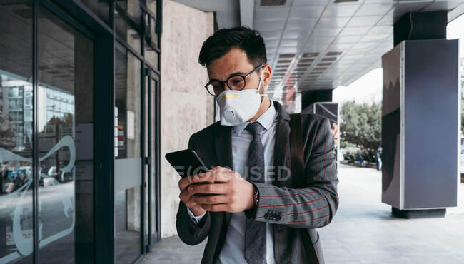 Business man with protective face mask using phone on city street — Stock Photo