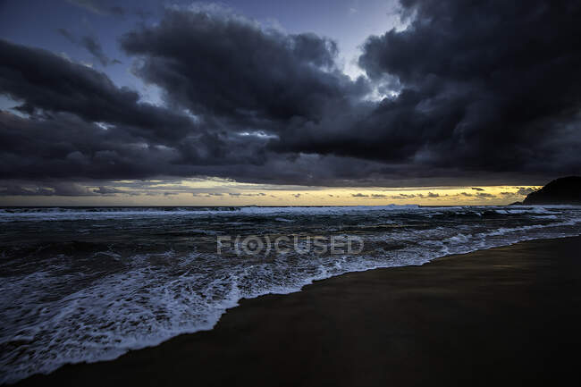 Захід сонця на пляжі з важкими хмарами. — стокове фото