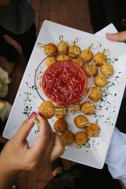 Appetizer plate from above with hand dipping food into sauce — Stock Photo