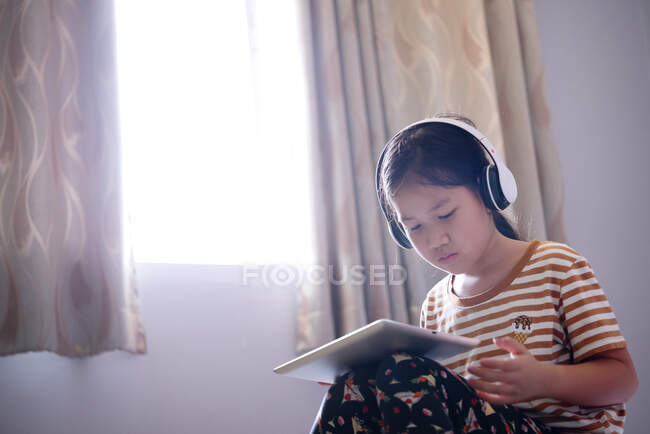 Meninas usam um tablet e ouvem música com fones de ouvido — Fotografia de Stock