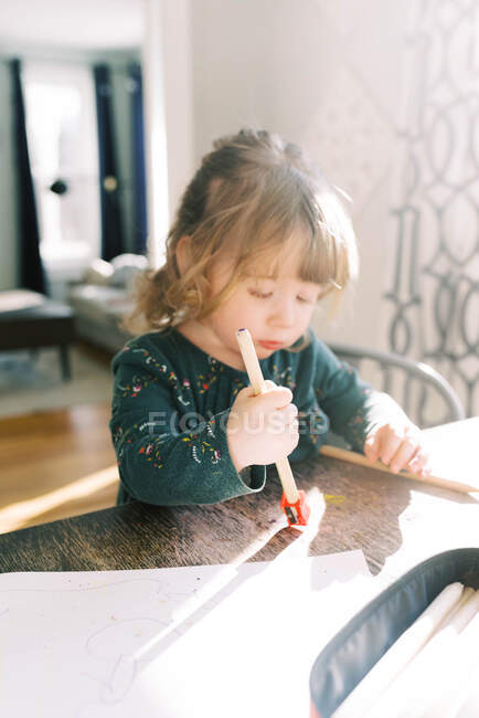 Маленька дворічна дівчинка загострює кольорові олівці . — стокове фото