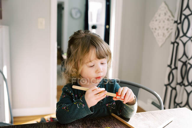 Маленька дворічна дівчинка загострює кольорові олівці . — стокове фото
