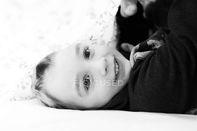 Happy five year old under a blanket and smiling into the camera. — Stock Photo