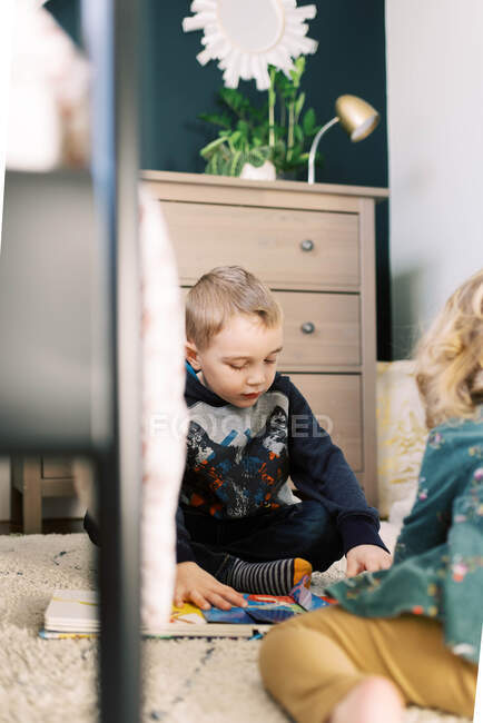 Siblings reading books together on the floor. — Stock Photo