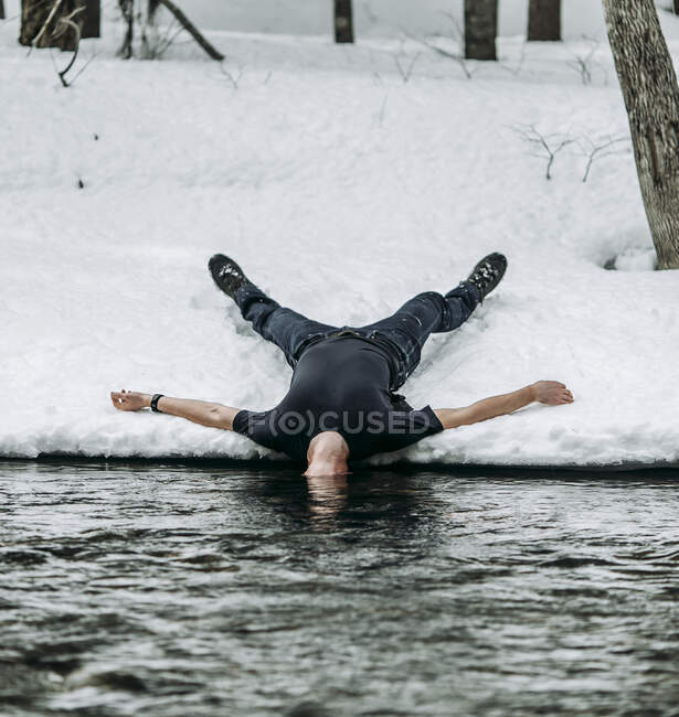 Homem encontra-se em volta na neve espalhar águia com cabeça subaquática no rio — Fotografia de Stock