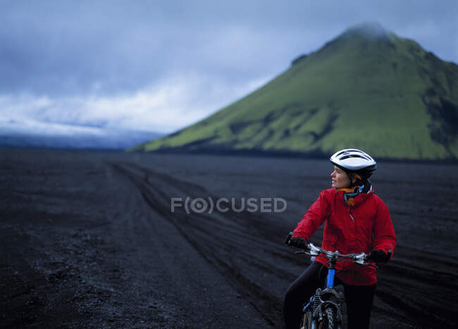 Mujer montando su bicicleta en Maelifellssandur en las tierras altas de Islandia - foto de stock