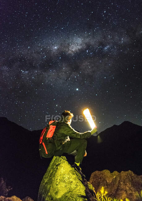 Young man sitting on a stone in the Andes mountains observing the gala — Stock Photo