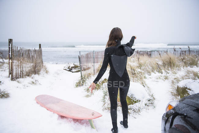 Woman going surfing in winter snow — Stock Photo