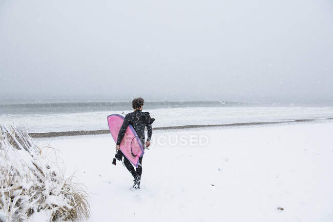 Homem que vai surfar durante a neve de inverno — Fotografia de Stock