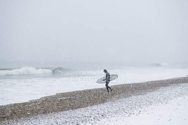 Чоловік збирається серфінг під час зимового снігу — стокове фото