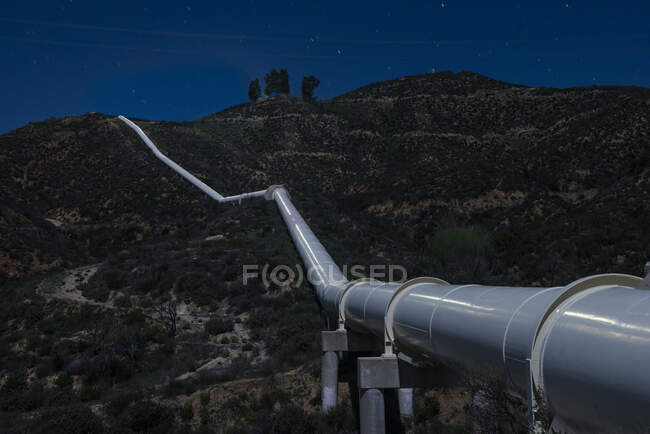 Oleoducto corre a través de montañas en el sur de California por la noche - foto de stock