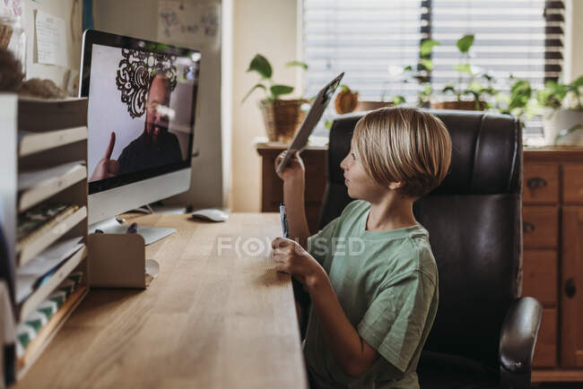 Side view of school aged boy getting thumbs up from online teach — Stock Photo