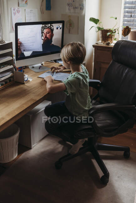 Elementary age boy tomando clases en línea de profesor durante isola - foto de stock