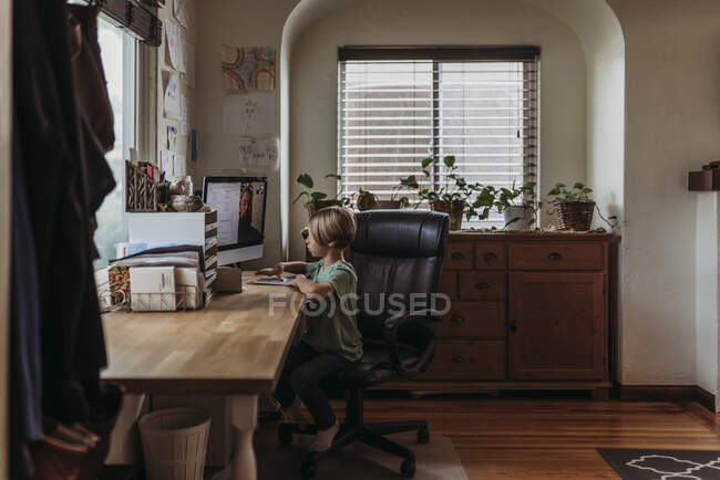 Weite Sicht auf einen kleinen Jungen, der während der Isolation Online-Unterricht nimmt — Stockfoto