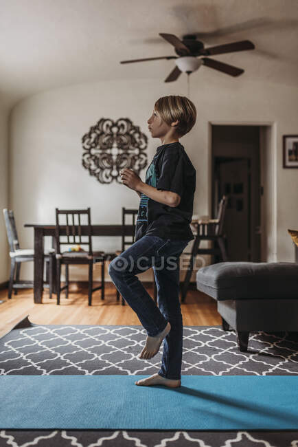 Мальчик, занимающийся йогой в гостиной во время изоляции — стоковое фото