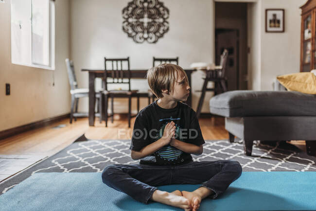 Young boy doing yoga in living room during isolation — Stock Photo