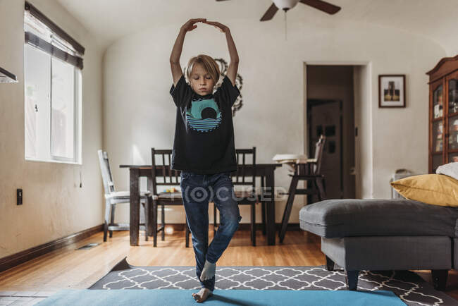 Молодий хлопчик робить йогу у вітальні під час ізоляції — стокове фото