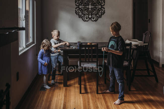 Siblings doing yarn project at home during isolation — Stock Photo