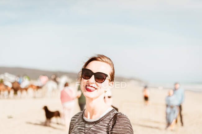 Молода жінка посміхається в сонячних окулярах на пляжі в Іспанії. — стокове фото