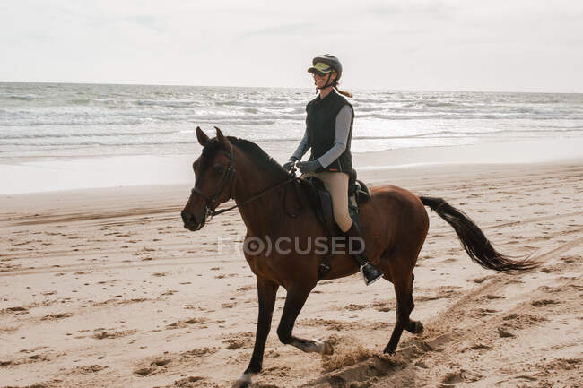Mulher montando cavalo andaluz na praia e sorrindo — Fotografia de Stock